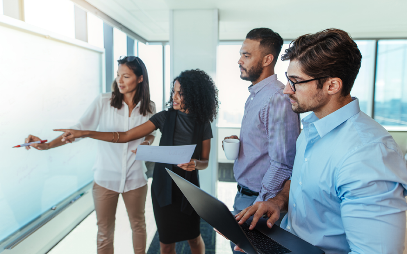 Group of people discussing beside a whiteboard